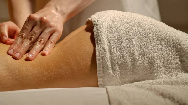 Spa salonunda sırt masajı. Yetenekli ellerle ve yumuşak havlularla masaj yapmanın rahatlatıcı etkisini hisset..