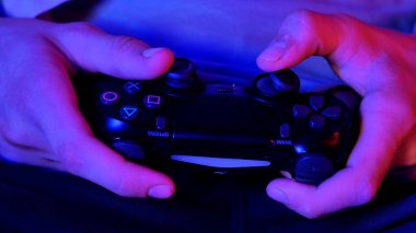 Parlayan düğmeleri olan bir video oyunu denetleyicisini tutan elleri kapat, tasarımın özelliklerini vurgula.