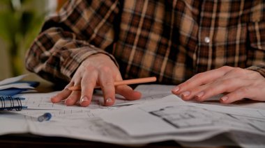 Mimari planları incelerken ellerinizi kapayın. Ayrıntılı çalışma planlarını gösteren bir kalemle..