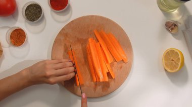 Baharat, domates ve limonla çevrili ahşap bir tahtanın üzerinde taze havuç dilimlemek..