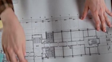 Bir kişi masasındaki ölçüm araçlarıyla çevrili kalemleri kullanarak mimari bir plan çiziyor. Tasarım, mimari süreç veya eğitim kavramı.