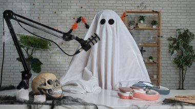Hayalet gibi giyinmiş, beyaz çarşaf giymiş biri mikrofonun önünde oturup Cadılar Bayramı teması üzerine komik bir podcast ya da blog hazırlıyor. Komedi, medya ve korkunç temalar için ideal.