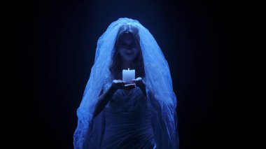 Karanlık bir sahnede tüyler ürpertici mavi bir ışık tarafından aydınlatılan şeffaf bir duvakla kaplanmış ölü bir gelin figürünün yer aldığı ürkütücü bir Cadılar Bayramı sahnesi. Hayalet gelin elinde yanan bir mum tutuyor..