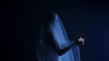 Karanlık bir sahnede tüyler ürpertici mavi bir ışık tarafından aydınlatılan şeffaf bir duvakla kaplanmış ölü bir gelin figürünün yer aldığı ürkütücü bir Cadılar Bayramı sahnesi. Hayalet gelin elinde yanan bir mum tutuyor..