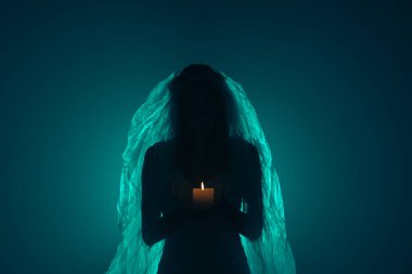 Karanlık bir sahnede tüyler ürpertici yeşil bir ışık tarafından aydınlatılan şeffaf bir duvakla kaplanmış ölü bir gelin figürünün yer aldığı ürkütücü bir Cadılar Bayramı sahnesi. Hayalet gelin elinde yanan bir mum tutuyor..