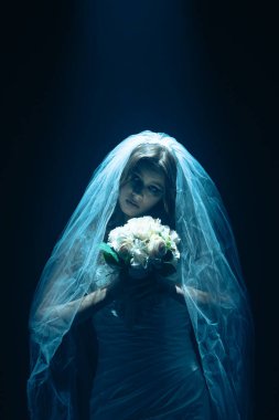 Karanlık bir sahnede tüyler ürpertici mavi bir ışık tarafından aydınlatılan şeffaf bir duvakla kaplanmış ölü bir gelin figürünün yer aldığı ürkütücü bir Cadılar Bayramı sahnesi. Hayalet gelin elinde bir buket tutuyor..