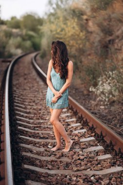 Mavi ipek gecelikli bir kadın tren rayları boyunca yalınayak yürüyor. Sonbaharın sonlarında doğal manzaralarla çevrili bir dişi. Doğal güzellik, şefkat ve kadınlık kavramı..