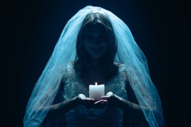 Karanlık bir sahnede tüyler ürpertici mavi bir ışık tarafından aydınlatılan şeffaf bir duvakla kaplanmış ölü bir gelin figürünün yer aldığı ürkütücü bir Cadılar Bayramı sahnesi. Hayalet gelin elinde yanan bir mum tutuyor..