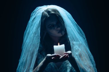 Karanlık bir sahnede tüyler ürpertici mavi bir ışık tarafından aydınlatılan şeffaf bir duvakla kaplanmış ölü bir gelin figürünün yer aldığı ürkütücü bir Cadılar Bayramı sahnesi. Hayalet gelin elinde yanan bir mum tutuyor..