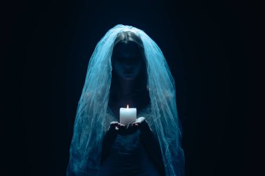 Karanlık bir sahnede tüyler ürpertici mavi bir ışık tarafından aydınlatılan şeffaf bir duvakla kaplanmış ölü bir gelin figürünün yer aldığı ürkütücü bir Cadılar Bayramı sahnesi. Hayalet gelin elinde yanan bir mum tutuyor..