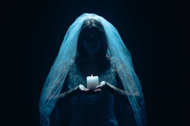 Karanlık bir sahnede tüyler ürpertici mavi bir ışık tarafından aydınlatılan şeffaf bir duvakla kaplanmış ölü bir gelin figürünün yer aldığı ürkütücü bir Cadılar Bayramı sahnesi. Hayalet gelin elinde yanan bir mum tutuyor..