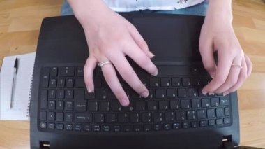 Ahşap bir zeminde otururken bilgisayarında daktilo yazan kişiye yaklaş.