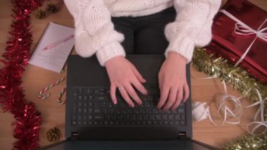 Noel / kış ortamında dizüstü bilgisayar kullanarak evden çalışan bir adam oyuncu küçük bir kedi uzanıp bir demet kurdele çalarken,