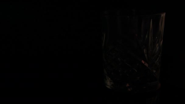 暗い背景に伝統的なウイスキーグラスがライトアップされます — ストック動画