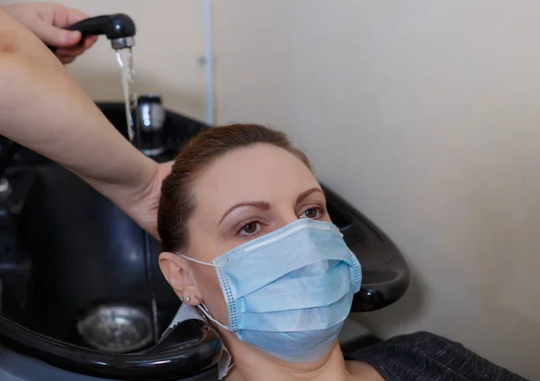Młoda Kobieta Masce Medycznej Myje Włosy Salonie Piękności Podczas Pandemii — Zdjęcie stockowe