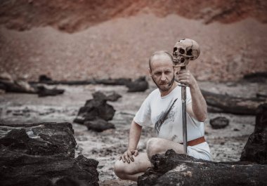 Savaştan sonra elinde bir hançerle dağlarda dinlenen savaşçı gezgin.