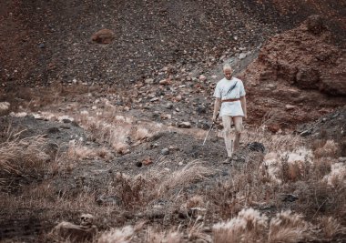 Savaştan sonra elinde bir hançerle dağlarda dinlenen savaşçı gezgin.