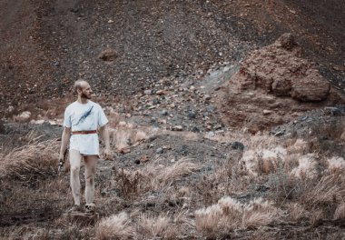 Savaştan sonra elinde bir hançerle dağlarda dinlenen savaşçı gezgin.