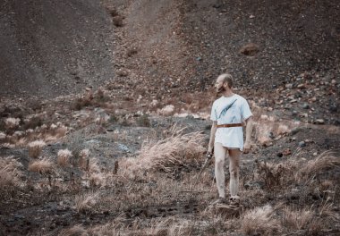 Savaştan sonra elinde bir hançerle dağlarda dinlenen savaşçı gezgin.