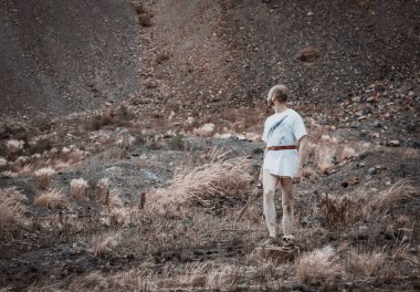 Savaştan sonra elinde bir hançerle dağlarda dinlenen savaşçı gezgin.