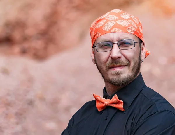 Bandana ve papyon takmış gülümseyen Avrupalı bir adamın portresi.