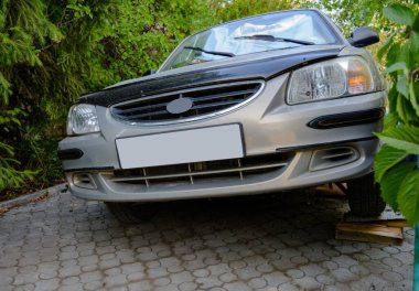 Yazın otoparkta gümüş yolcu vagonu ön tekeri yedek lastikle değiştirilmiş.