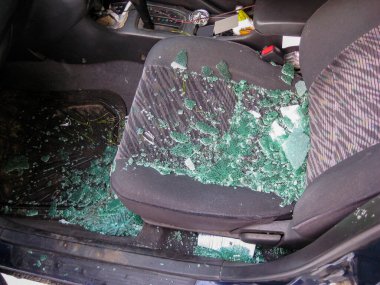 A broken window with splinters scattered across the interior of the car during a road accident close-up. blurred focus clipart