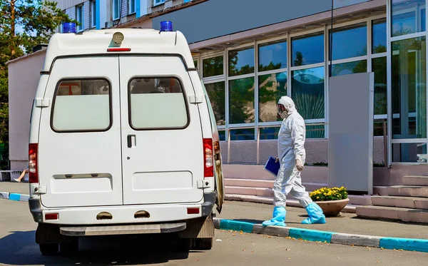 Bulaşıcı koruyucu giysi ve koruyucu maske giyen bir doktor kovid 19 koronavirüs karantinası sırasında hastaya gitmek üzere ambulansa gönderilir.