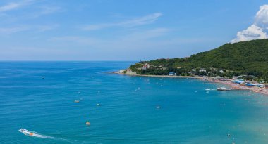 Dağın eteğinde turistlerle dolu bir plajı olan bir tatil beldesi.