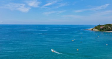 Dağın eteğinde turistlerle dolu bir plajı olan bir tatil beldesi.