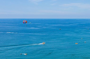 Dağın eteğinde turistlerle dolu bir plajı olan bir tatil beldesi.