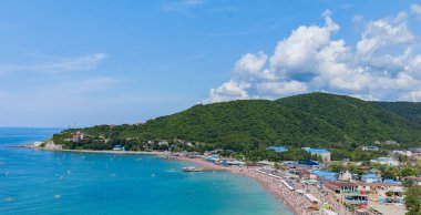 Dağın eteğinde turistlerle dolu bir plajı olan bir tatil beldesi.