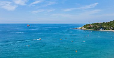 Dağın eteğinde turistlerle dolu bir plajı olan bir tatil beldesi.