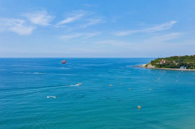Dağın eteğinde turistlerle dolu bir plajı olan bir tatil beldesi.