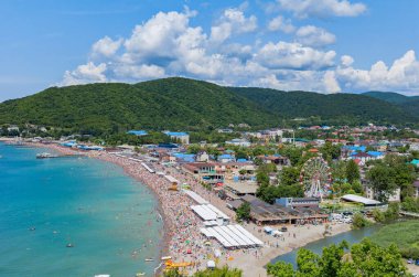 Dağın eteğinde turistlerle dolu bir plajı olan bir tatil beldesi.