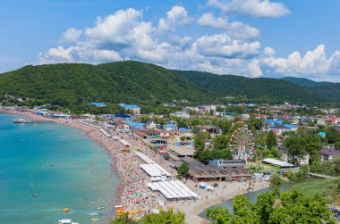 Dağın eteğinde turistlerle dolu bir plajı olan bir tatil beldesi.