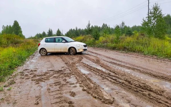 passenger white hatchback stuck on the road in rainy weather on a country road. blurry focus