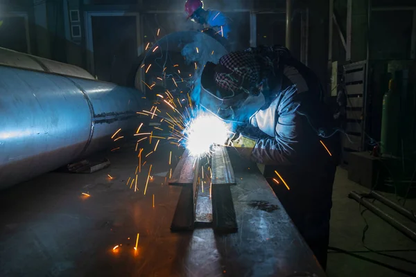 Worker performs welding of metal structures. Semi-automatic manual welding. MIG welding.