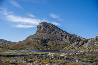 Görkemli ve engebeli bir dağ zirvesi Norveç 'in engin manzarasına hakim, sakin bir dağlık göl üzerinde yükselen kayalık yamaçlarına. Çevresindeki arazi vahşi ve çorak, alçak bitki örtüsü ise sonbahar renklerinin izlerini taşıyor..