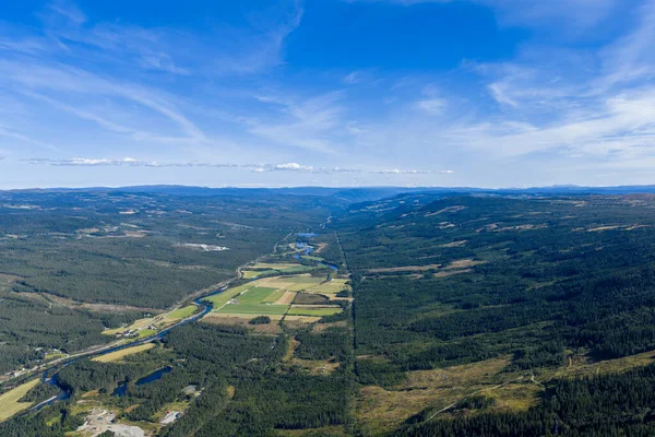 Geniş bir nehir vadisinin uçsuz bucaksız mavi gökyüzünün altında uzanan nefes kesici panoramik hava manzarası. Vadiden akan kıvrımlı bir nehir her iki taraftaki yemyeşil ormanlarla çevrili..
