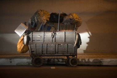 Balnear io Camboriu, Santa Catarina, Brezilya - 18 Kasım 2016: Geri dönüşümlü malzeme taşıyan ahşap vagon temiz bir caddeye gece park edilmiş, bir araba farıyla aydınlatılıyor