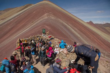 Vinicunca, Cusipata, Peru - June 08, 2017: Tourists arriving in the top of Seven Colors Mountain, or Vinicunca Mountain, one of the most famous peaks in Peru, a must see destination in the country clipart