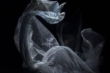 Siyah arka planda rüzgarda süzülen bir plastik parçasının soyut bileşimi