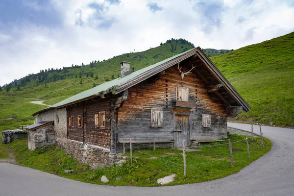 尾根ビームの下に鹿の角を持つオーストリアの山の古い木造住宅や石造りの家 — ストック写真