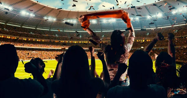 Group of cheering fans watch a sport championship on stadium. Their team wins and everybody are celebrating this event. People are dressed in casual cloth.