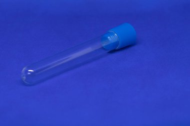 Mavi başlıklı plastik kan toplama tüpü. Fotoğrafın mavi bir arka planı var.