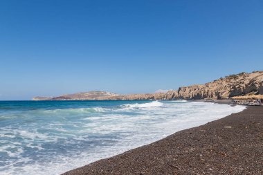 Yunanistan 'ın Santorini adasındaki Vlychada sahili ve plajı. Arka planda mavi gökyüzü ve denizde dalgalar.