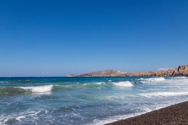 Yunanistan 'ın Santorini adasındaki Vlychada sahili ve plajı. Arka planda mavi gökyüzü ve denizde dalgalar.
