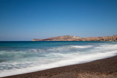 Yunanistan 'ın Santorini adasındaki Vlychada sahili ve plajı. Arka planda mavi gökyüzü ve denizde dalgalar.