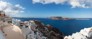 Yunanistan 'ın Santorini adasındaki Oia kasabası. Arka plan koyu bulutlu mavi bir gökyüzü. Beyaz evlerin manzarası